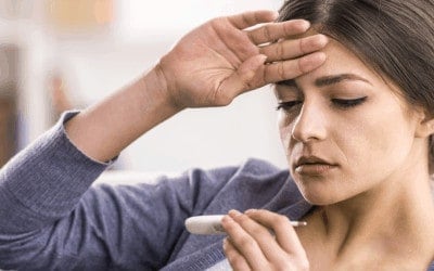 jonge vrouw kijkt op koortsthermometer