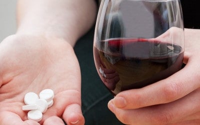 femme avec un verre de vin et des médicaments